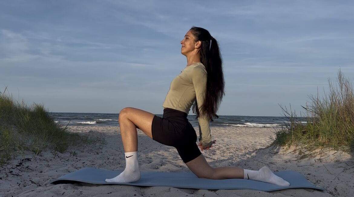 Aitekin in tiefer Ausfallschritt-Pose am Strand mit erhobener Brust